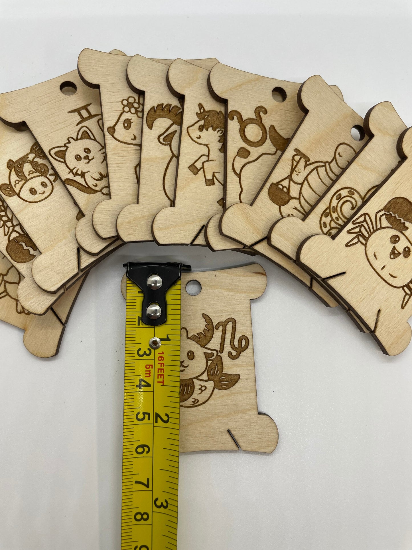 Wooden bobbins with animal illustrations and a measuring tape for scale on a white background
