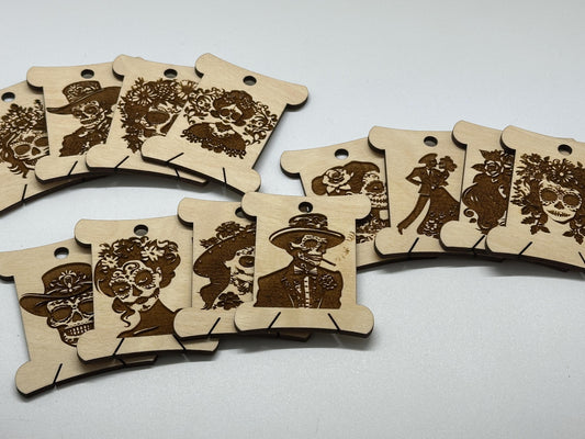 Wooden bobbins with laser-cut designs of faces on a white background