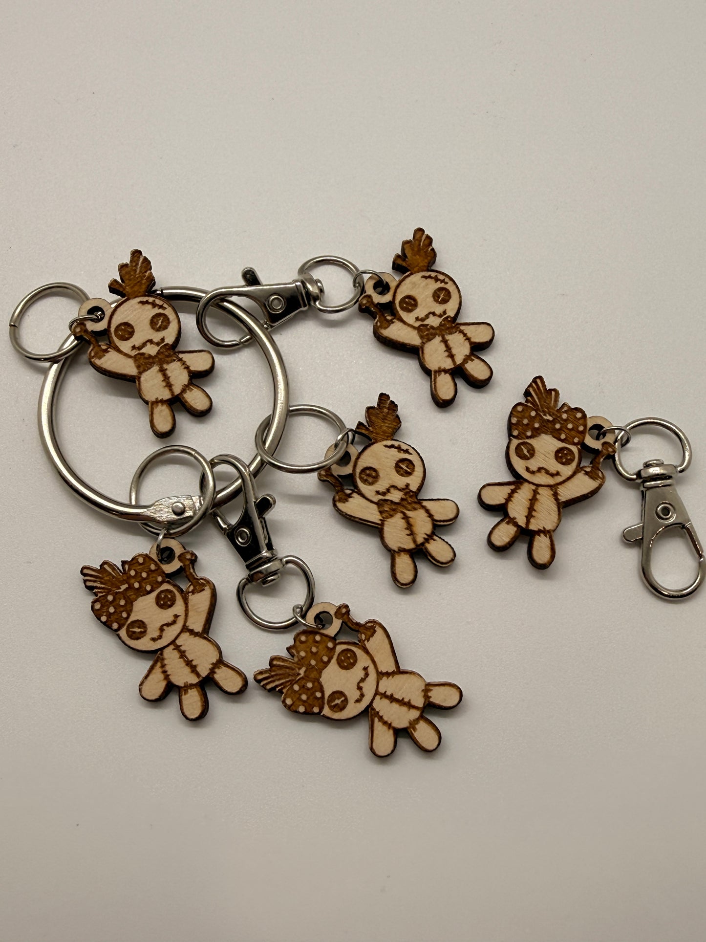 Set of wooden keychains shaped like voodoo doll characters on a beige background