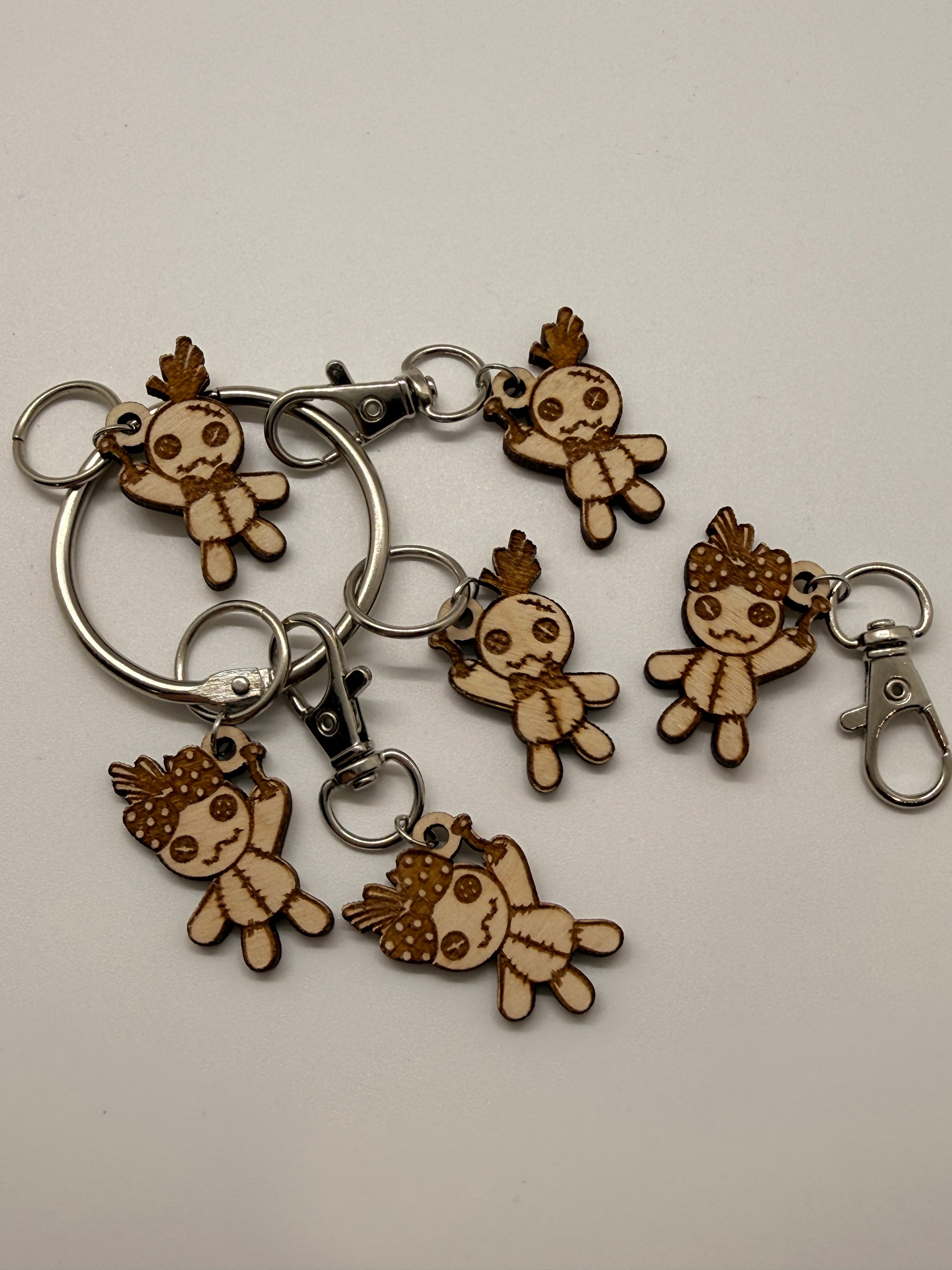 Set of wooden keychains shaped like voodoo doll characters on a beige background