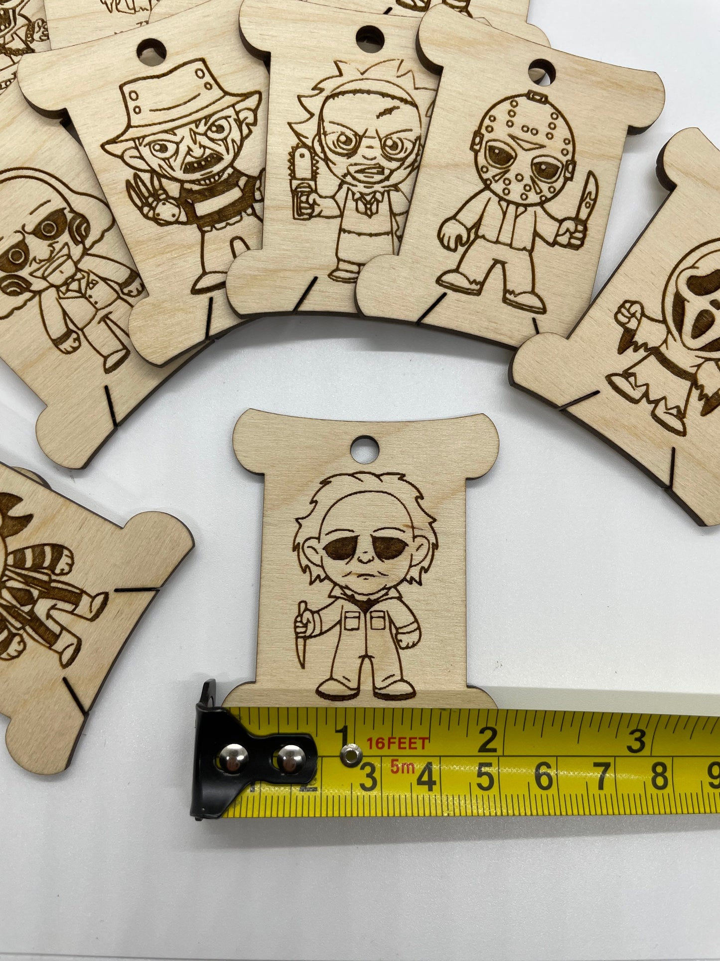 Wooden bobbins with engraved characters and a measuring tape for scale on a white background