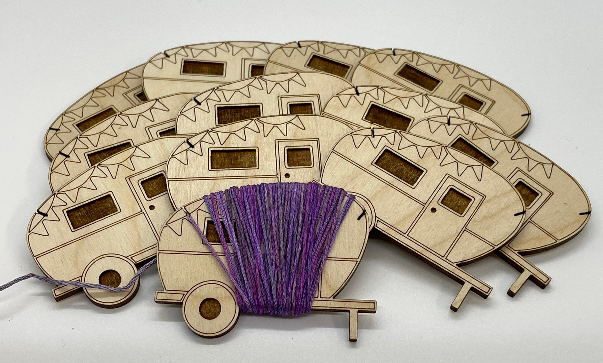 Wooden model of a camper with purple yarn on a white background