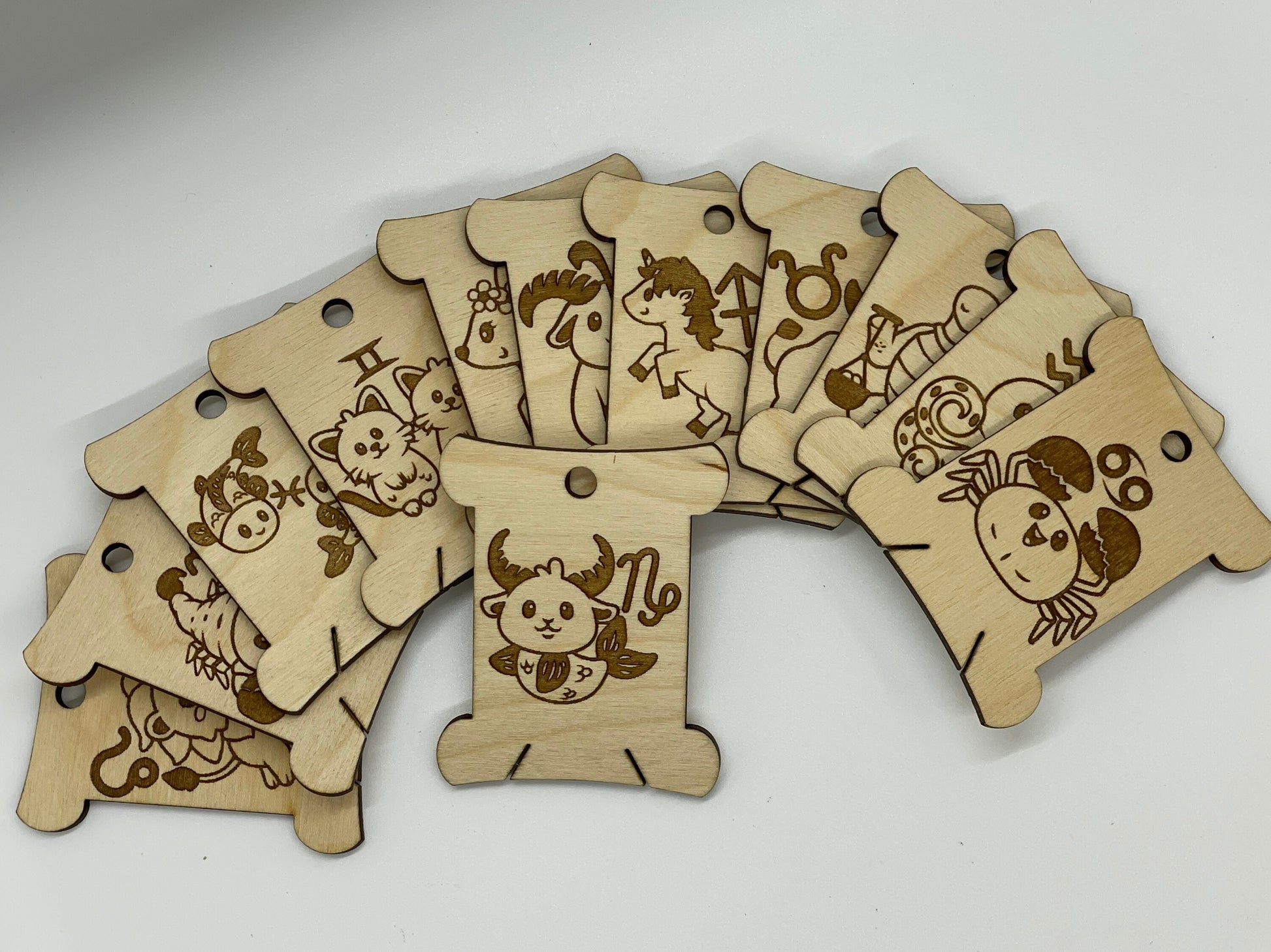Wooden zodiac sign bobbins arranged on a white surface