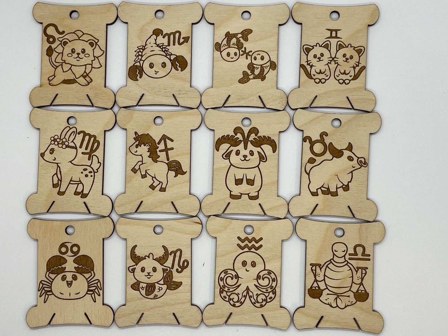 Set of wooden bobbins with engraved zodiac signs on a white background