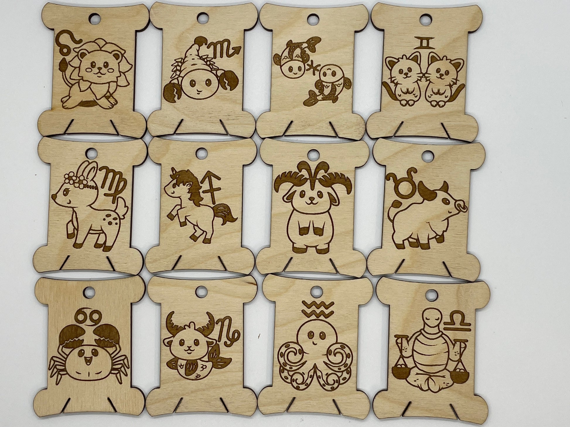 Set of wooden bobbins with engraved zodiac signs on a white background