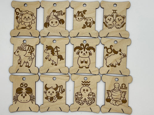 Set of wooden bobbins with engraved zodiac signs on a white background