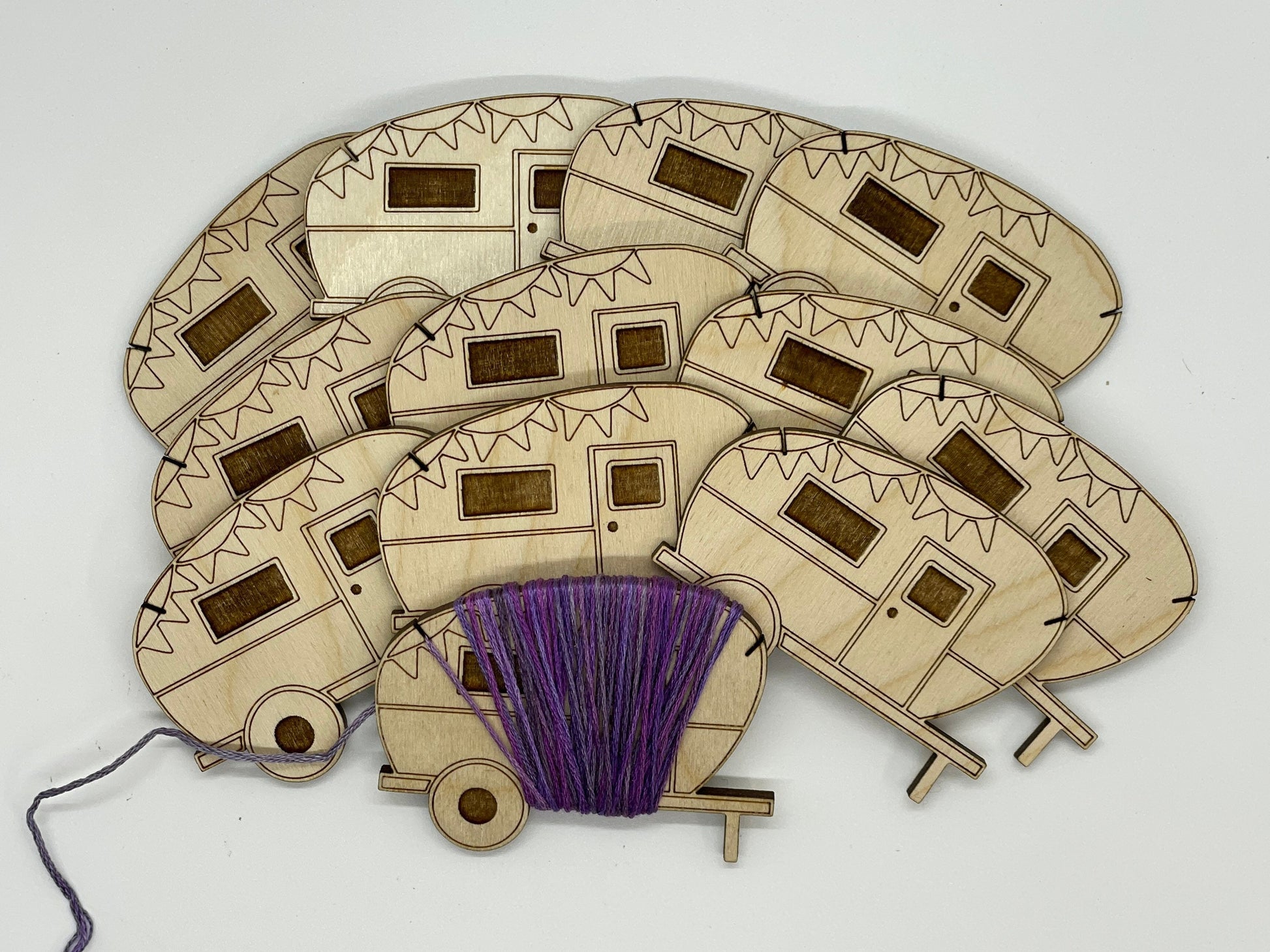 Wooden campers with a spool of purple thread on a white background