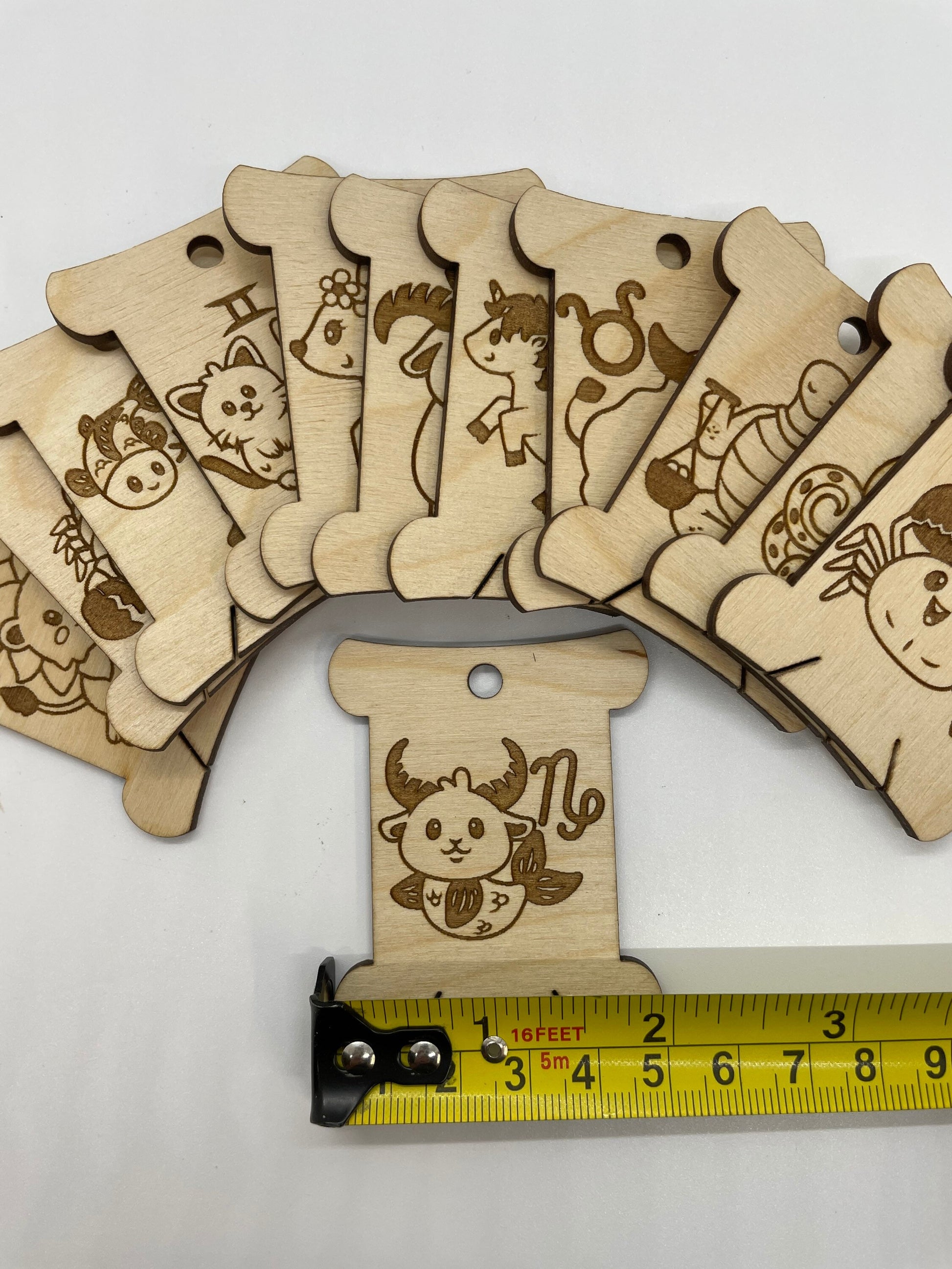 Set of wooden bobbins with animal illustrations on a white background, with a tape measure for scale.