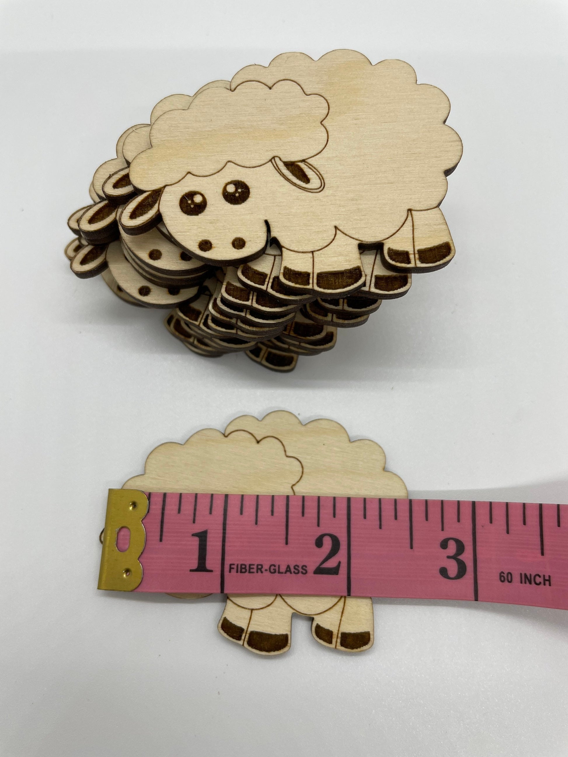 Wooden sheep cutouts with a measuring tape for scale on a white background