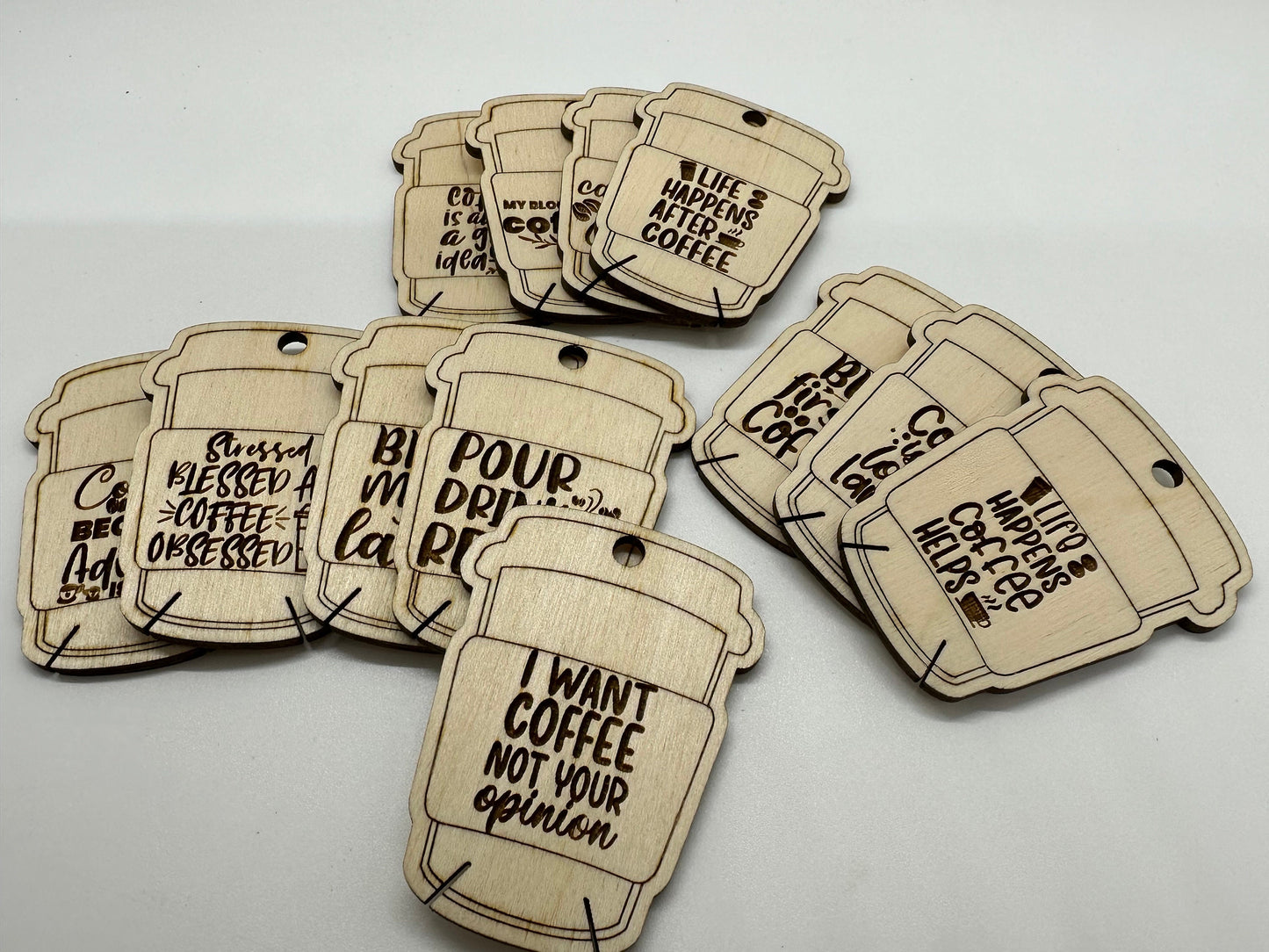 Wooden coffee-themed bobbins with humorous sayings on a white background