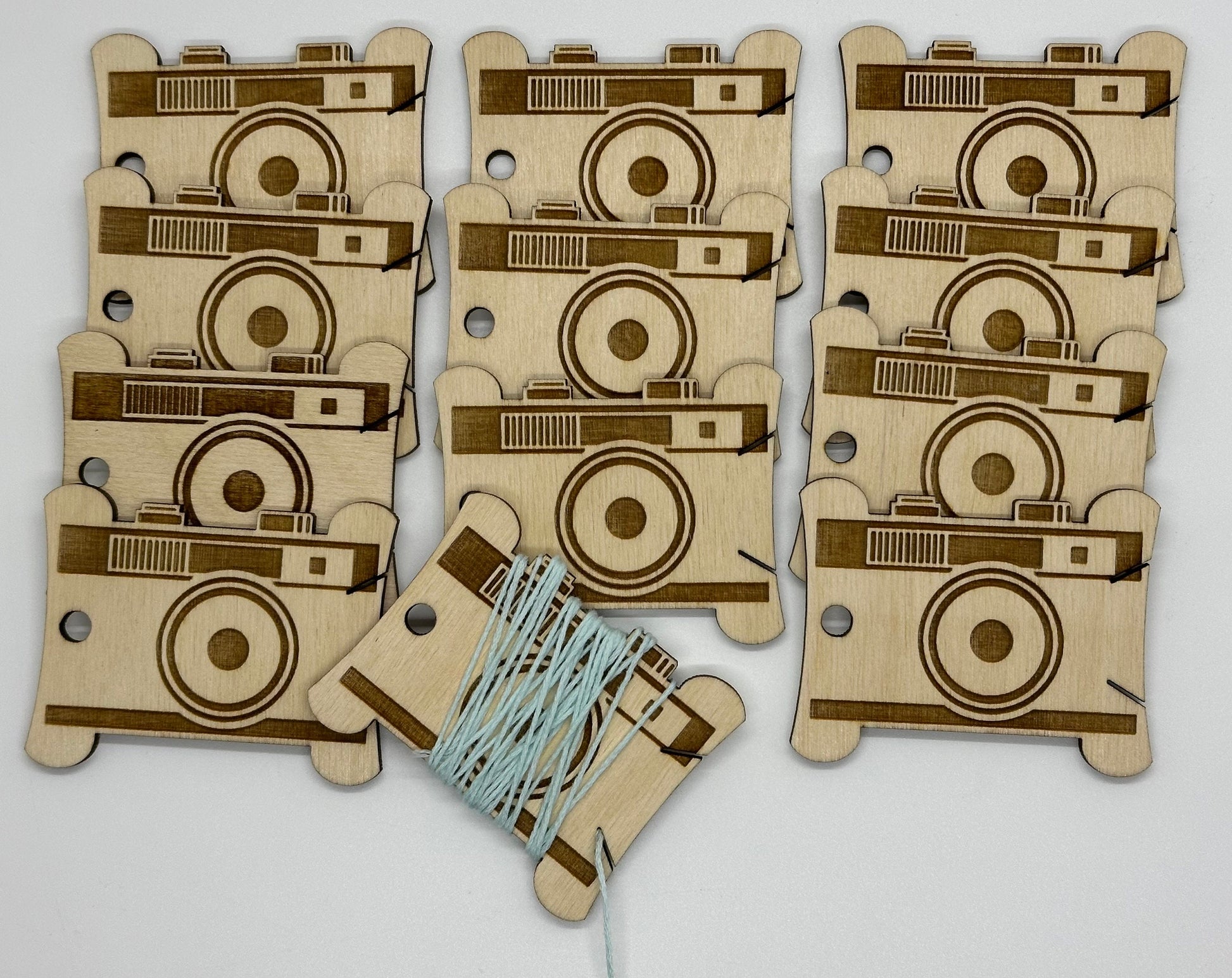 Wooden camera-shaped bobbins with a string on a light gray background