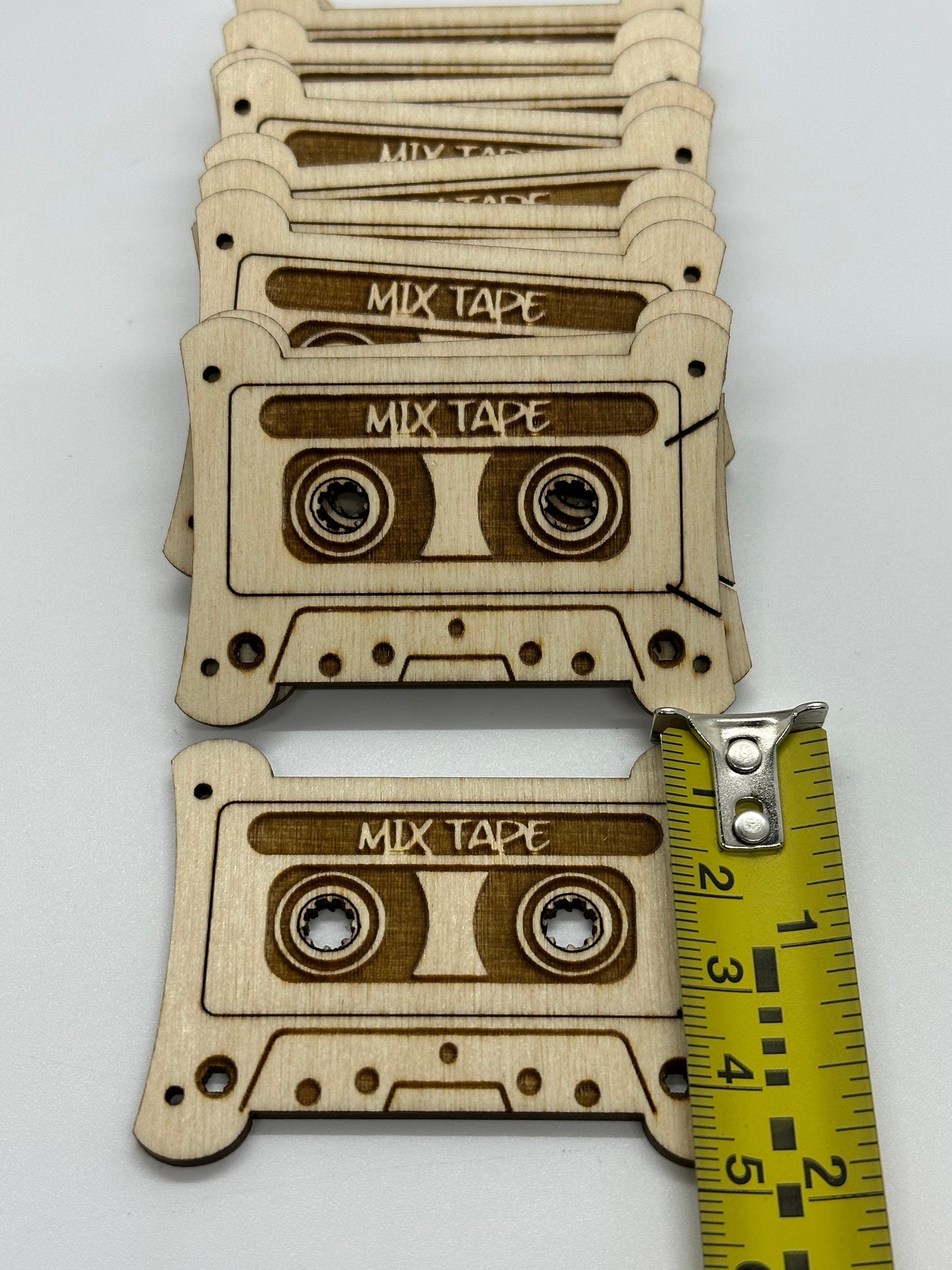 Wooden mixtape bobbins with a measuring tape for scale on a white background