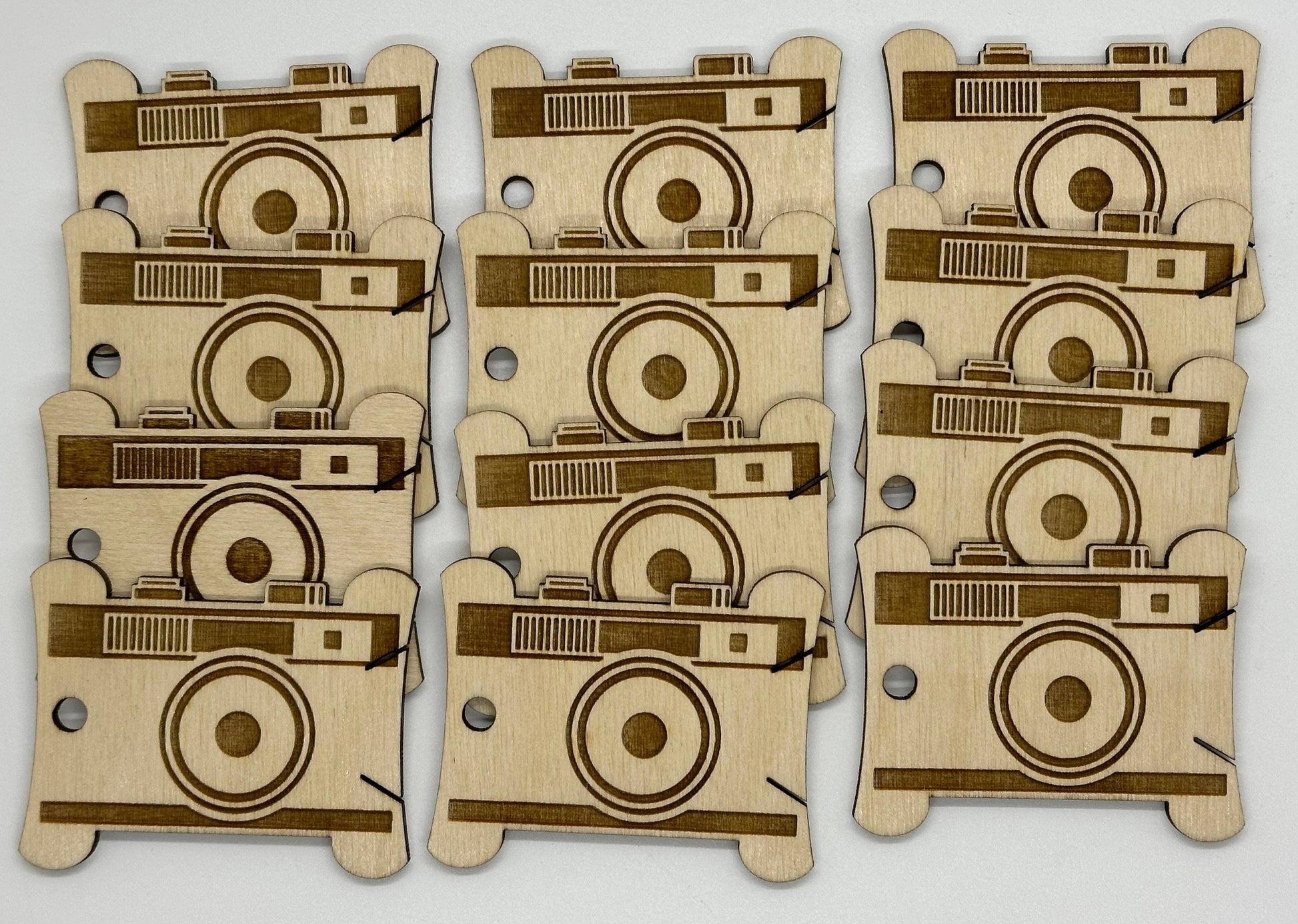 Set of laser-cut wooden camera-shaped pieces on a white background
