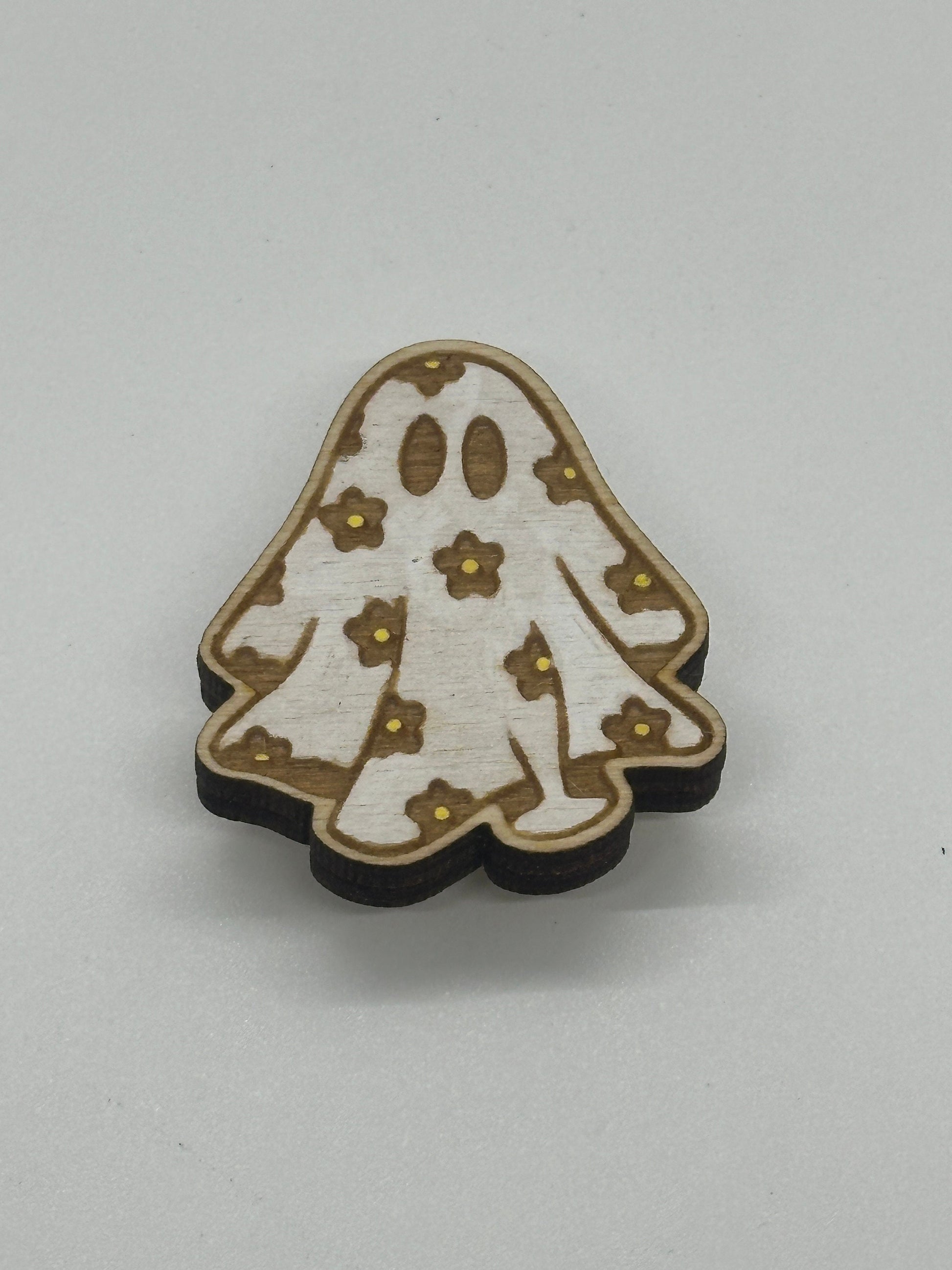 Wooden ghost-shaped minder with flower patterns on a light gray background