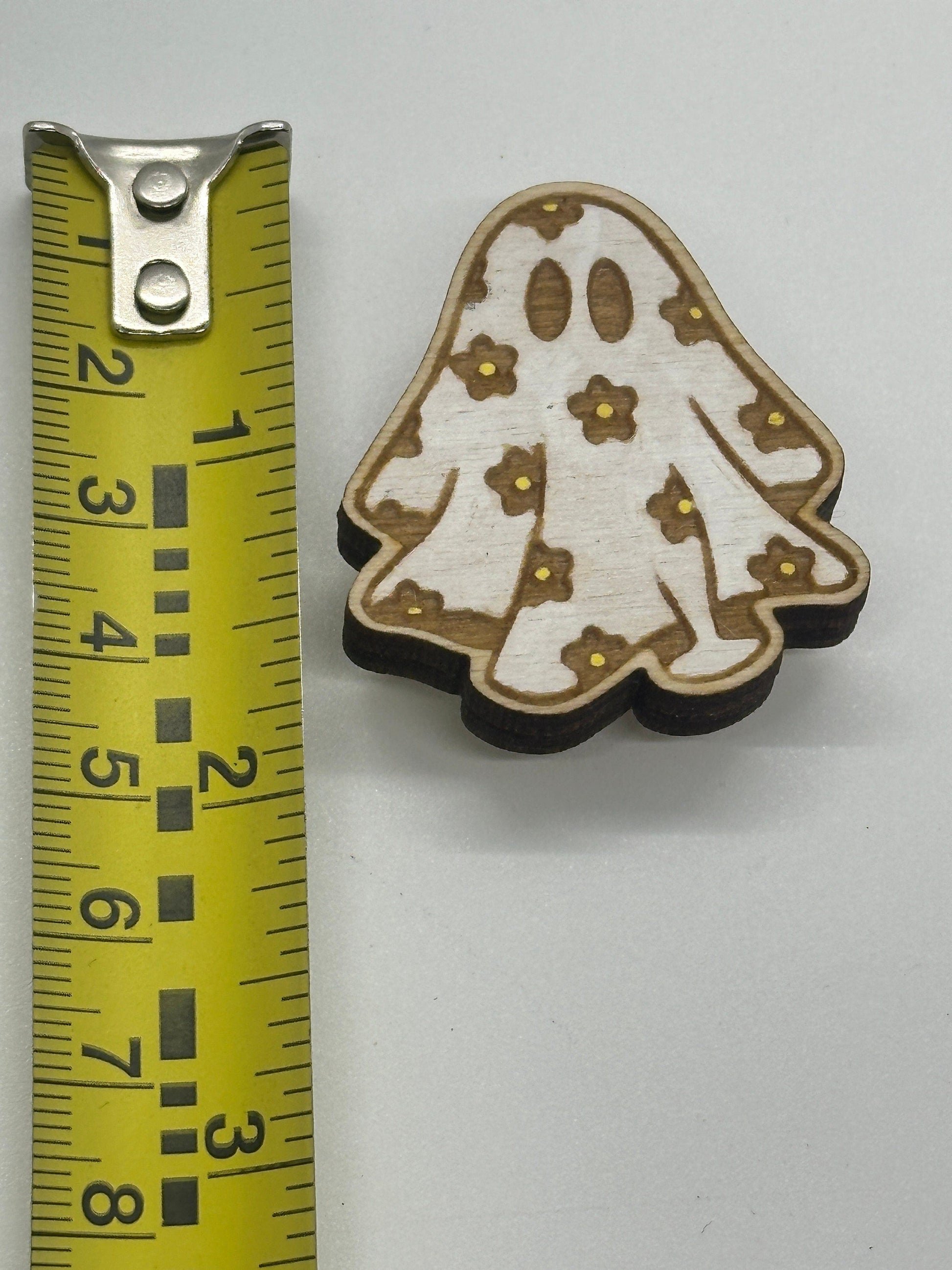 Decorative wooden piece with floral patterns on a white background, measured against a tape measure.