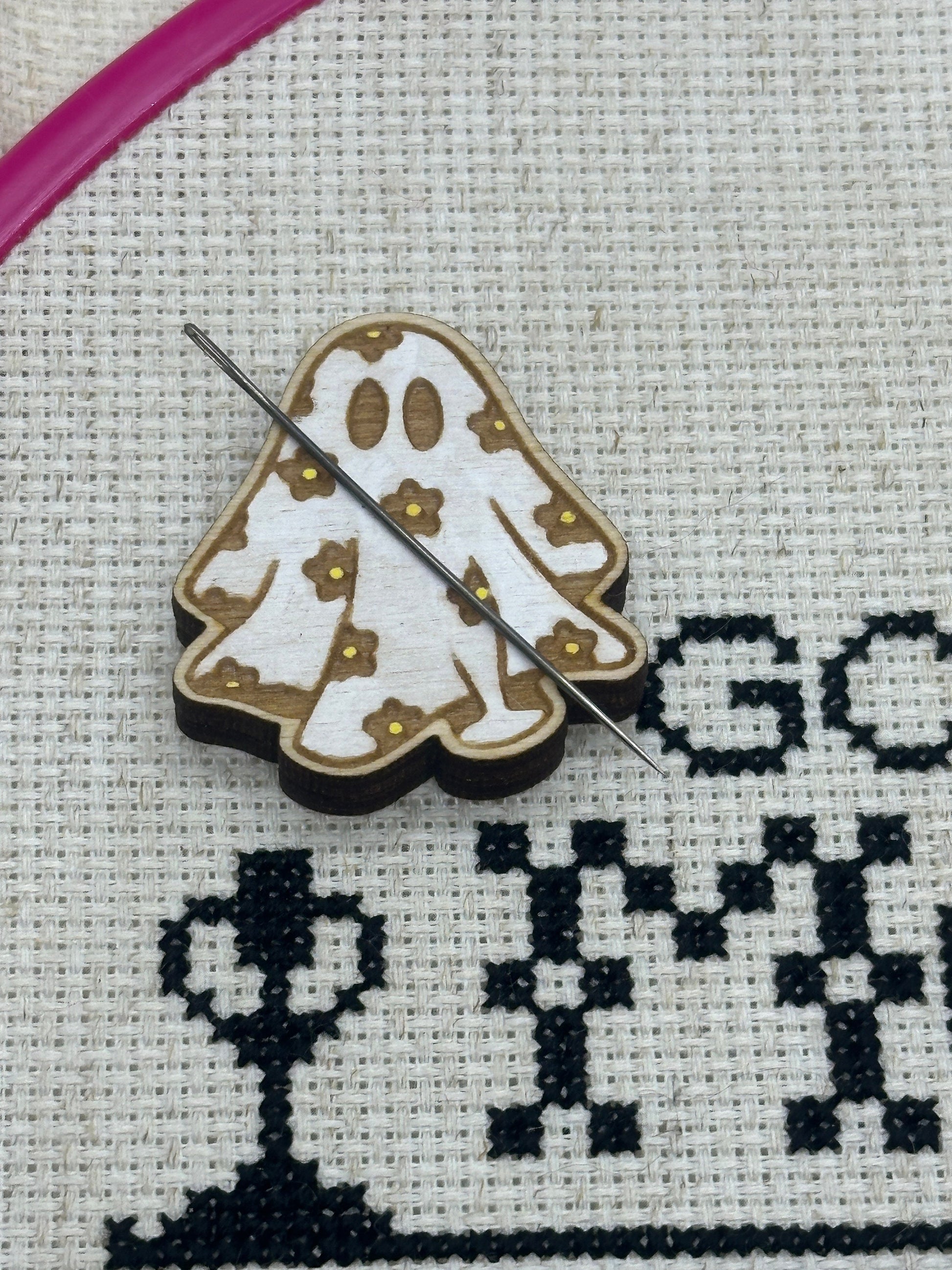 Cross-stitching project with a ghost design and needle threaded through fabric.