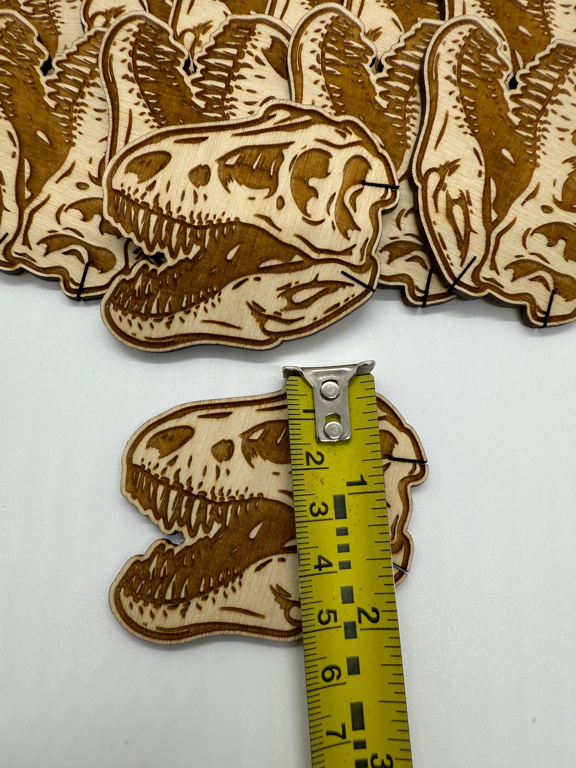 Wooden dinosaur skeleton cutouts with a measuring tape for scale on a white background