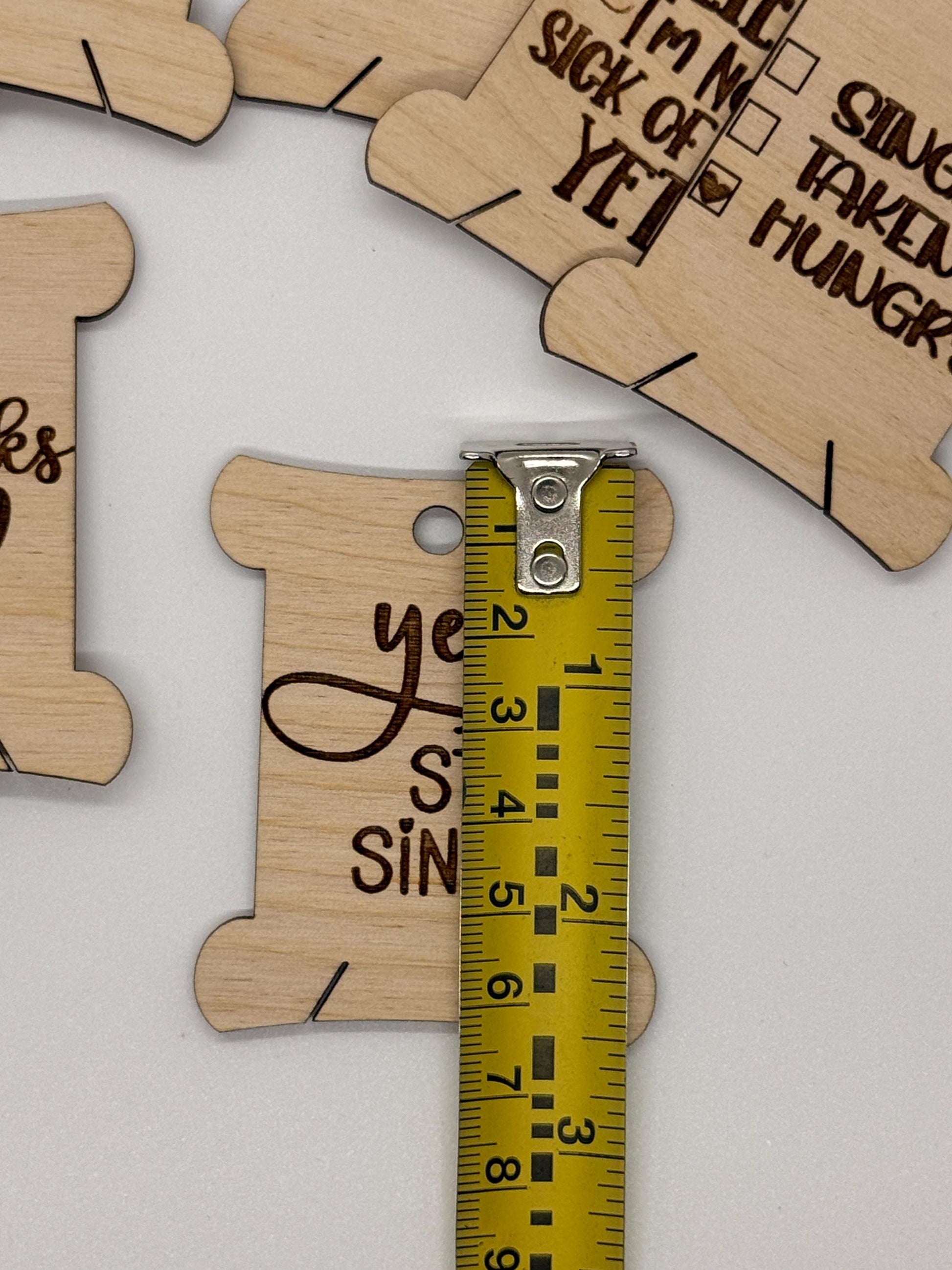 Wooden cutouts with engraved text and a tape measure for scale on a white background