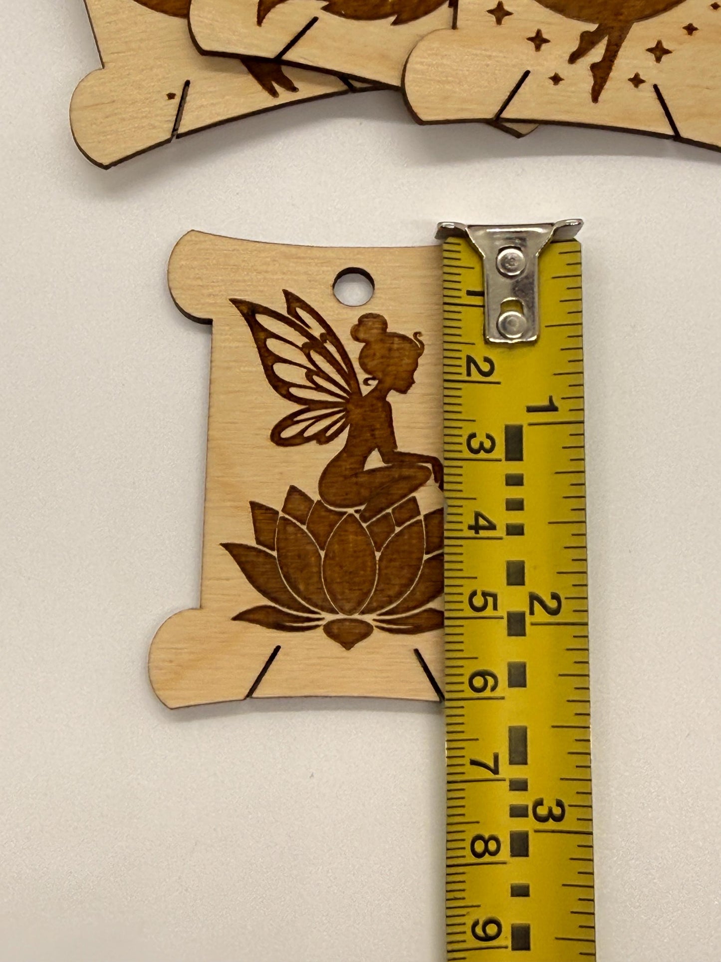 Wooden fairy and lotus design with a ruler for scale on a beige background