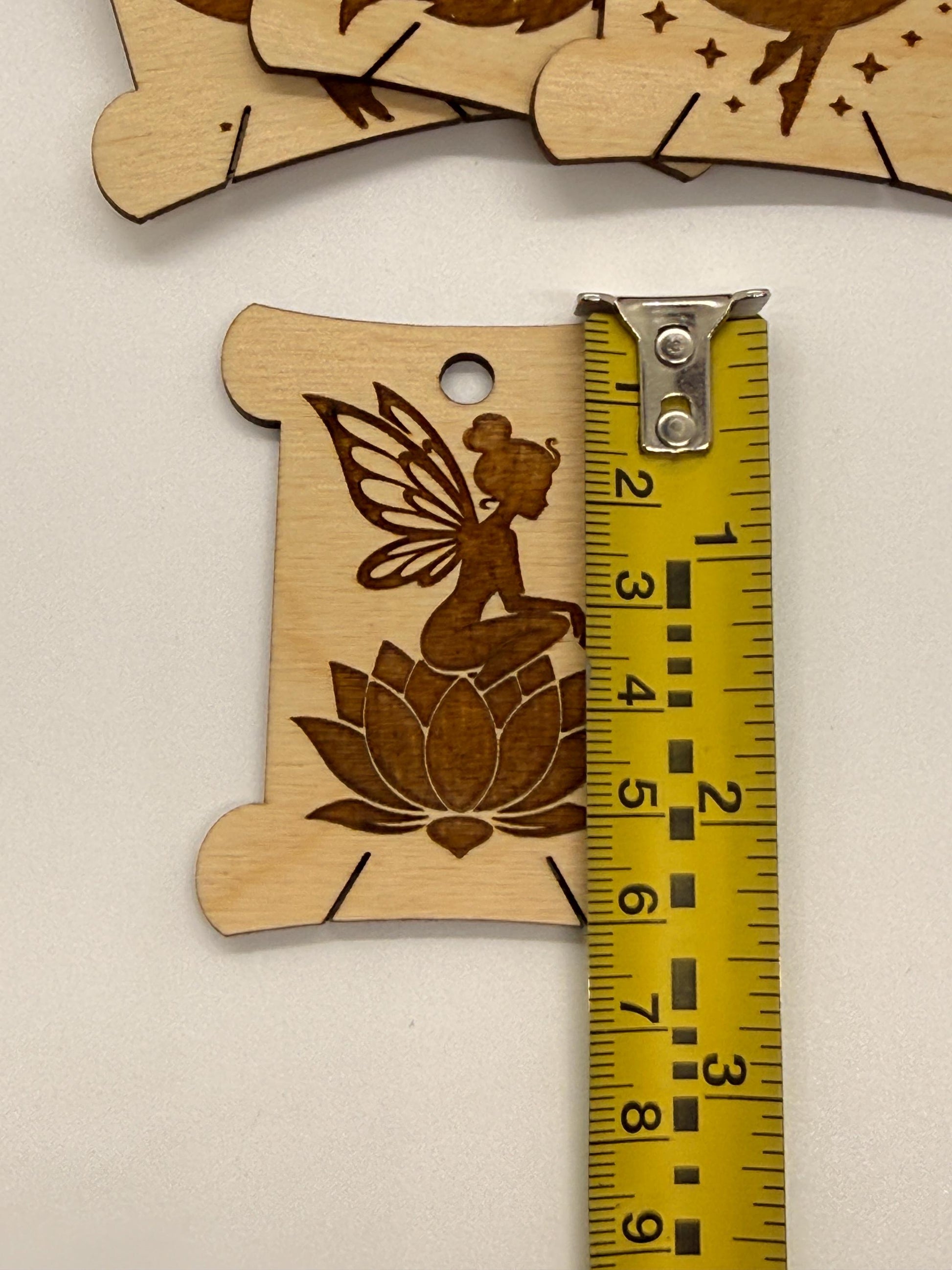 Wooden fairy and lotus design with a ruler for scale on a beige background