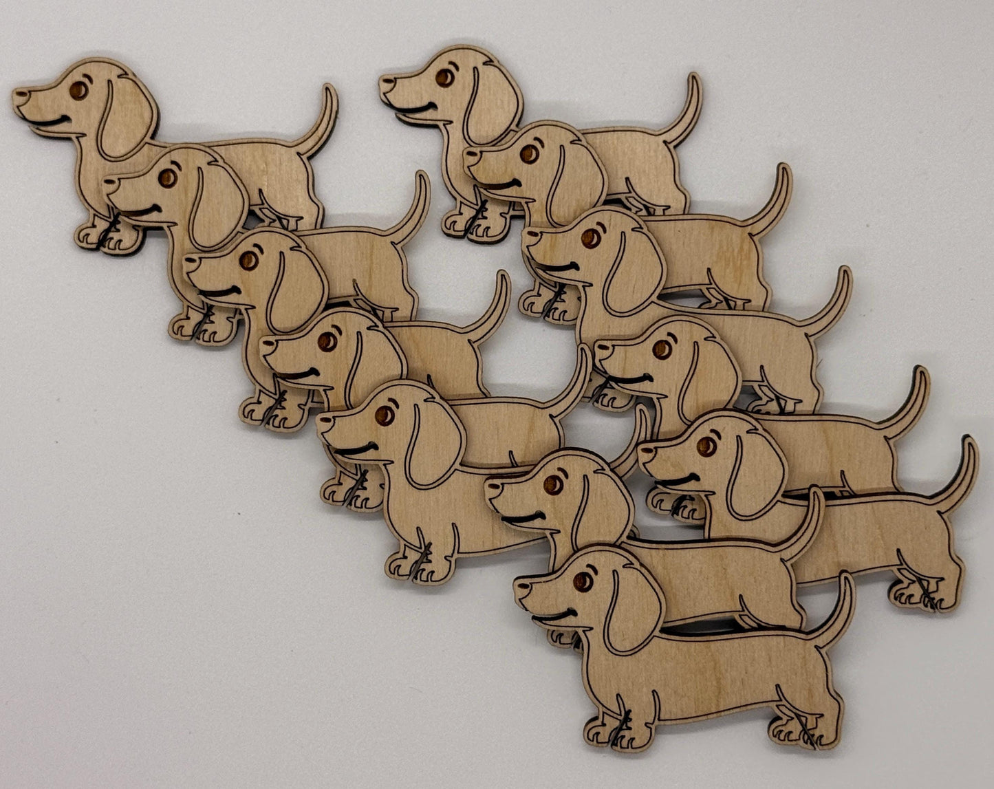 Wooden cutouts of dachshunds arranged in a pattern on a white background